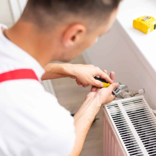 Close-up of mature mechanic hands repairing heating system.