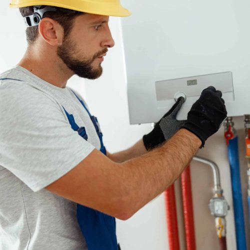 Serious technician setting the new gas boiler for hot water and heating. Manual work, maintenance concept