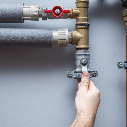Man working at pipes. Turning on or turning off water supply in the boiler room. Plumbing concept.