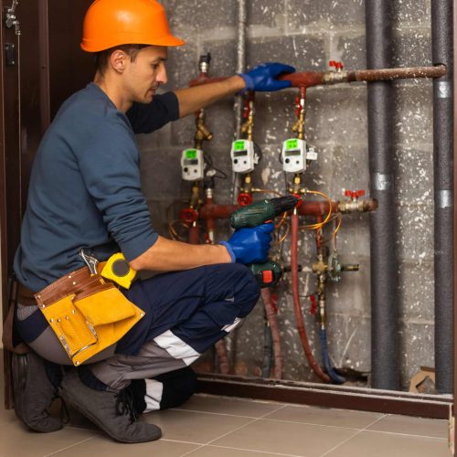 Maintenance engineer checking technical data of heating system equipment in a boiler room. Plumber installing pressure meter for house heating system.